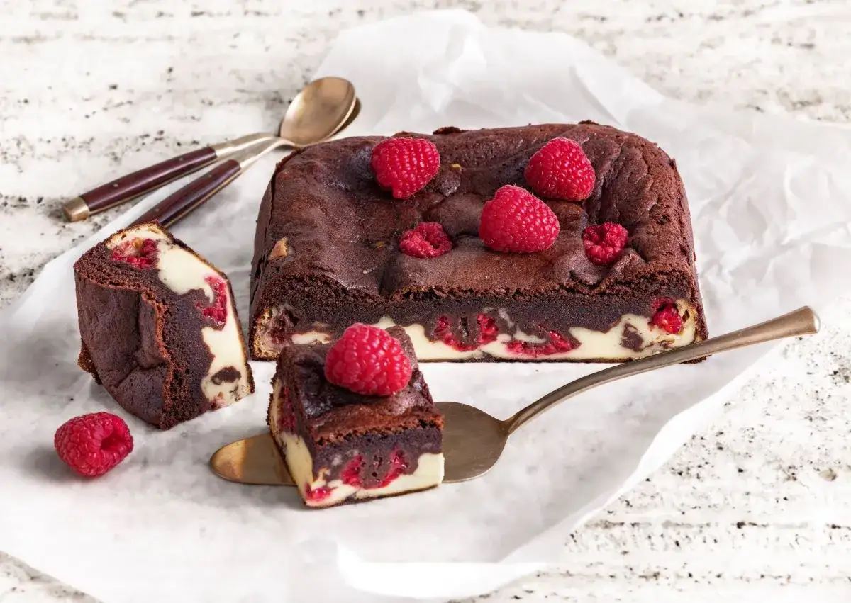 Pyszny sernikobrownie z malinami, udekorowany świeżymi owocami. Idealny deser na każdą okazję.