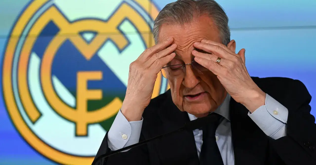 Prezes Realu Madryt, Florentino Pérez, z dłońmi na czole, na tle logo klubu.