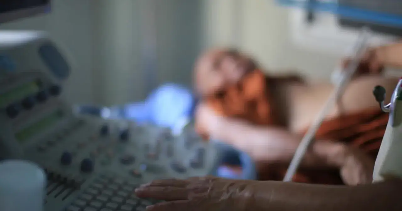 Przygotowanie do badania echo serca. Lekarz wykonuje USG pacjentowi, skupiając się na obrazie na monitorze.
