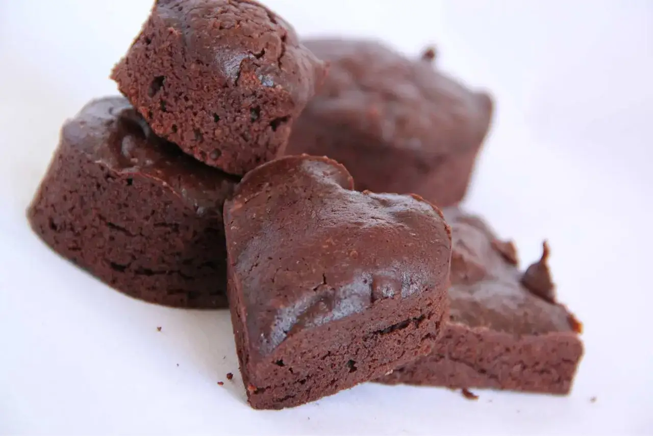 Un tas de financiers au chocolat, certains en forme de c&oelig;ur, sur fond blanc.