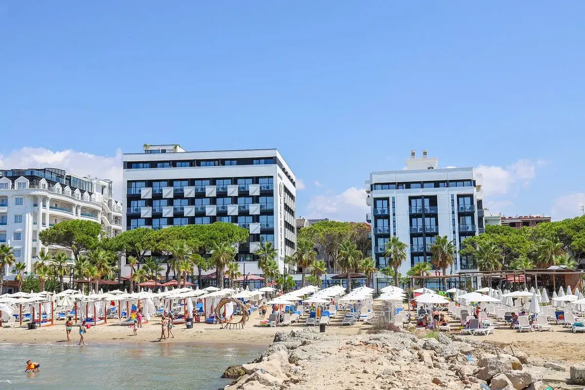 Słoneczny dzień na plaży, idealny na fafa mel holiday. Hotelowe budynki, palmy i leżaki tworzą wakacyjny klimat.