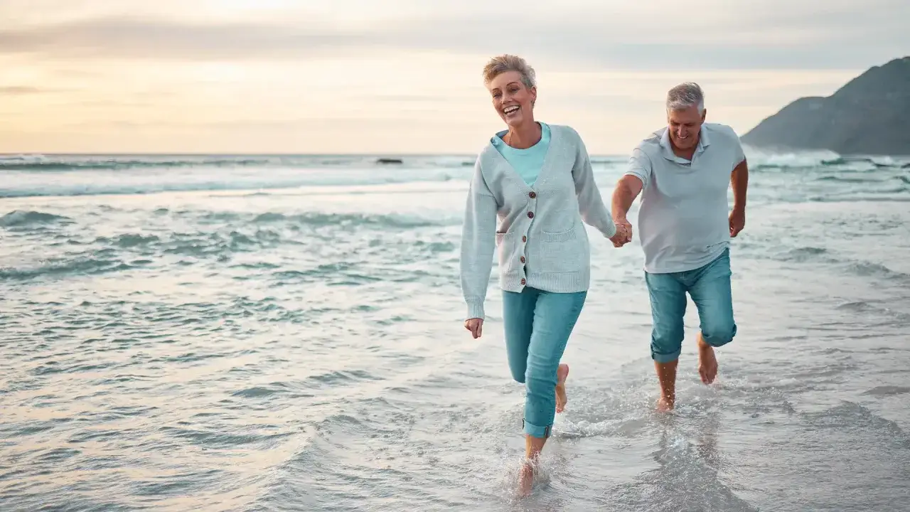 Gl&uuml;ckliches Paar am Strand, das die Sonne genie&szlig;t. Ein zuschuss pflegekasse urlaub macht solche Momente m&ouml;glich.