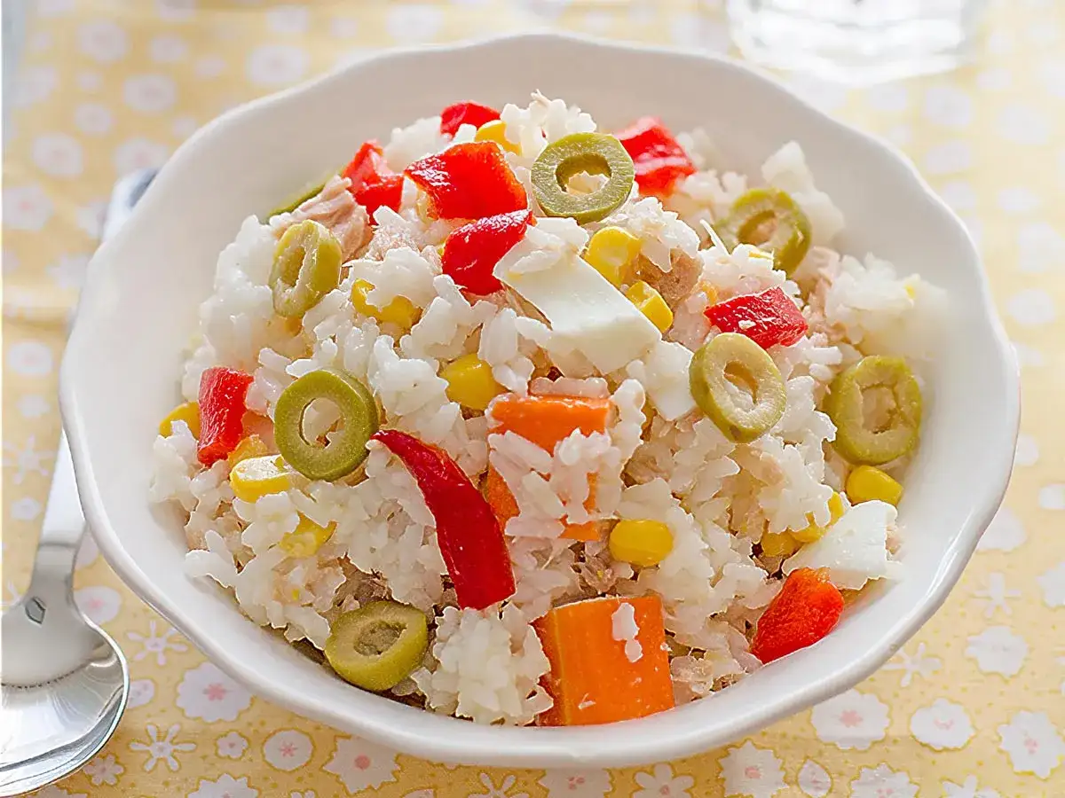 Deliciosa ensalada de arroz con mayonesa, trozos de pimiento rojo, aceitunas verdes, maíz y huevo duro.