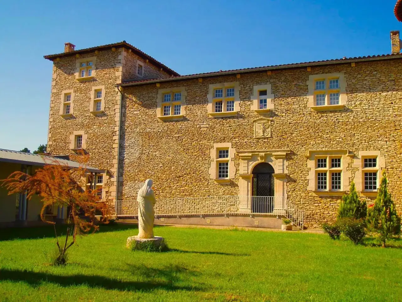 Statue de la Vierge devant la fa&ccedil;ade en pierre de la blauvac abbaye, sous un ciel bleu &eacute;clatant.