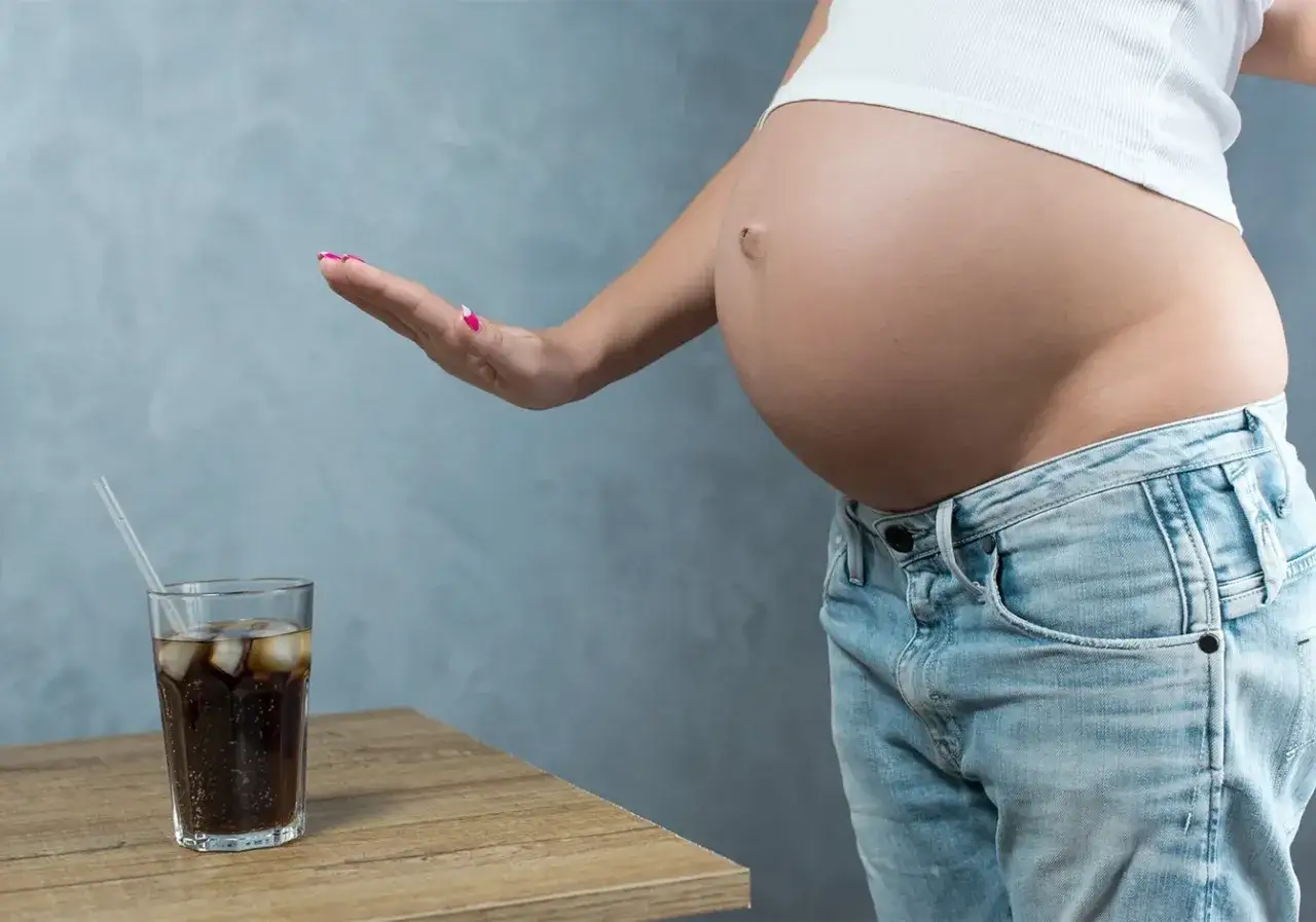 Schwanger und verzichtet auf Cola. Eine Hand weist das Glas mit dem kohlens&auml;urehaltigen Getr&auml;nk ab.