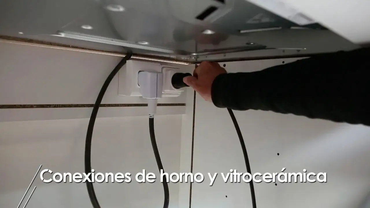 Mano conectando el enchufe para horno y vitrocer&aacute;mica a la toma de corriente.