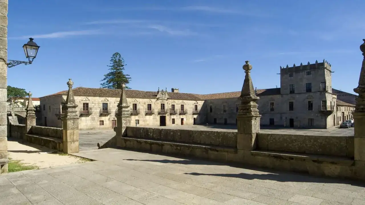 El Pazo de Fefi&ntilde;anes, un conjunto arquitect&oacute;nico de piedra con torre&oacute;n y patio, bajo un cielo azul.