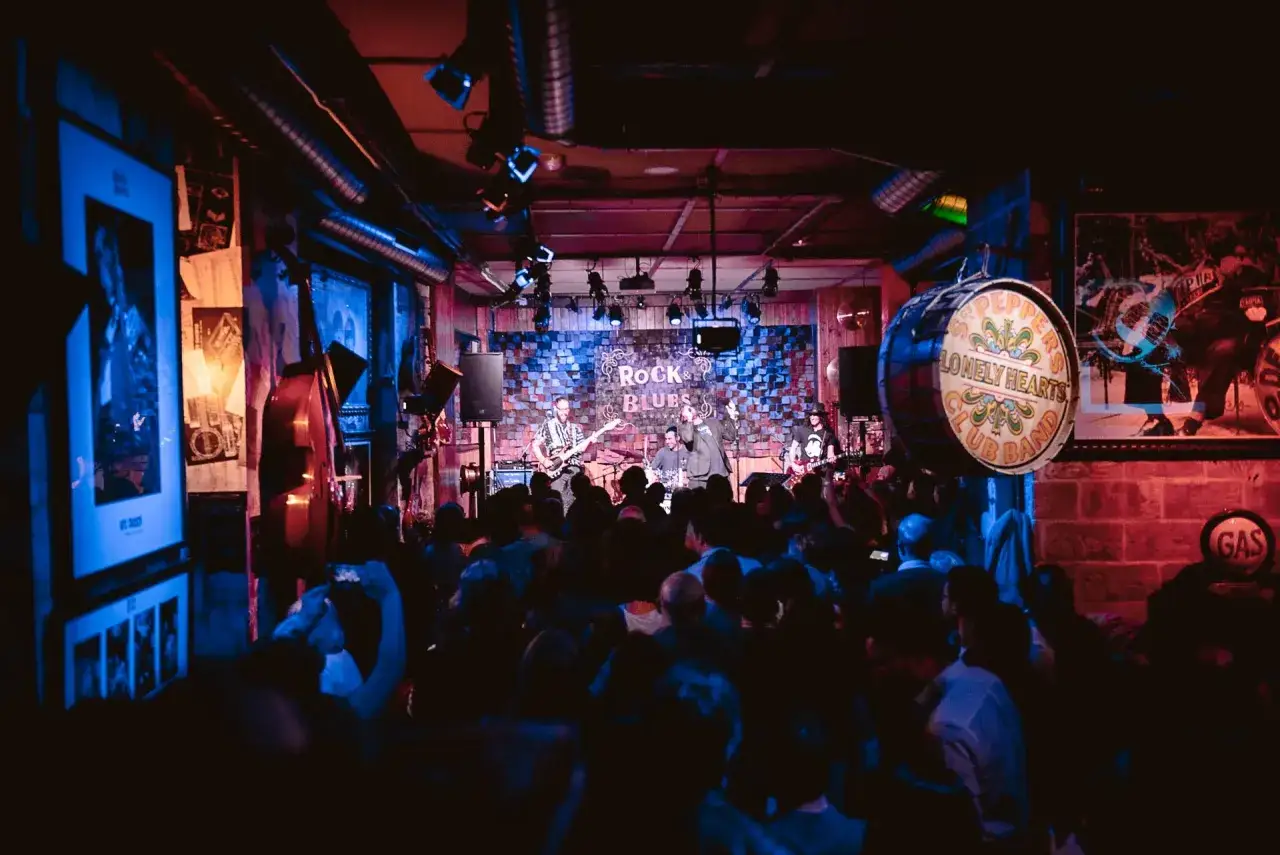 Una banda toca en un escenario iluminado en el Zaragoza Psych Fest. El público, con móviles en alto, disfruta del concierto.