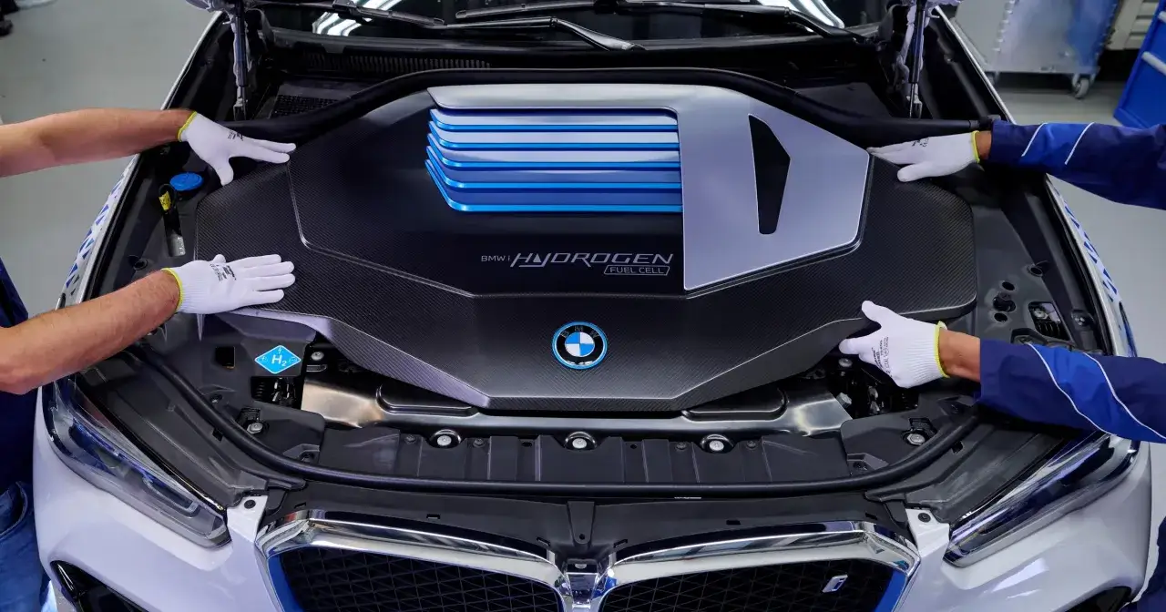 Ręce w białych rękawiczkach montują osłonę silnika BMW i HYDROGEN FUEL CELL.