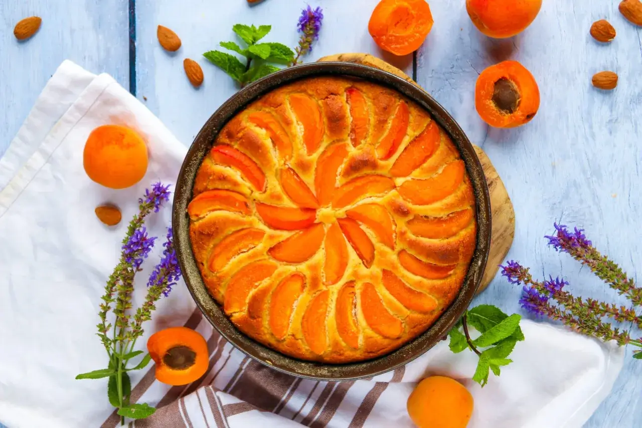 Un d&eacute;licieux moelleux aux abricots, parsem&eacute; d'amandes et d&eacute;cor&eacute; de fleurs violettes et de menthe fra&icirc;che.