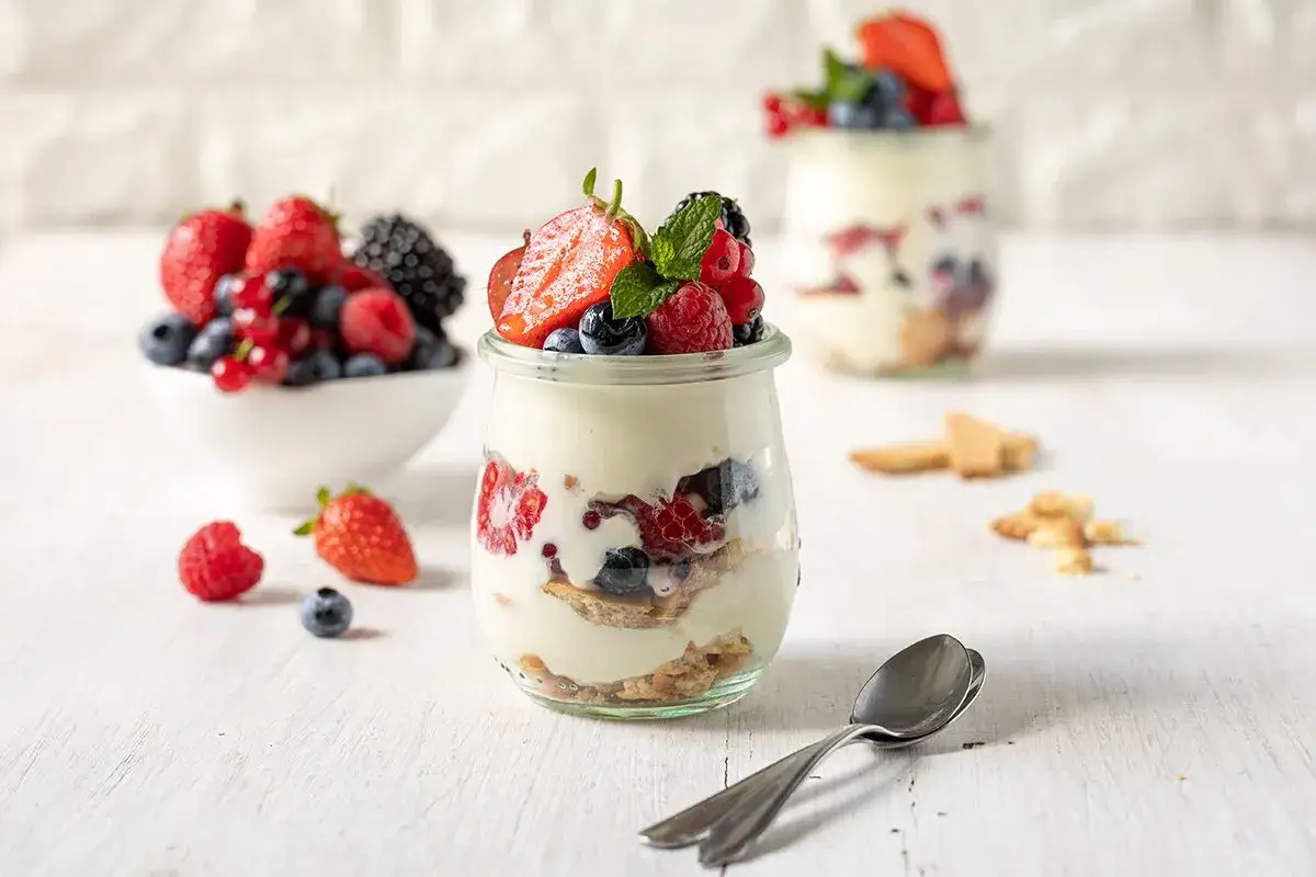 Leckeres Dessert mit Mascarpone, frischen Beeren und Granola in einem Glas.