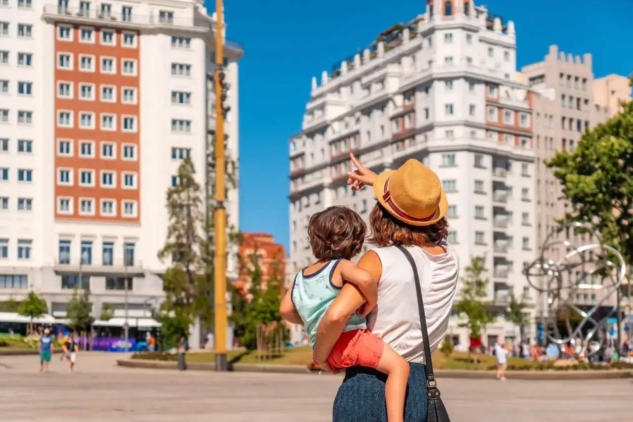 Madre con niño en brazos, señalando algo en la ciudad. Un destino ideal entre los países para viajar con niños.