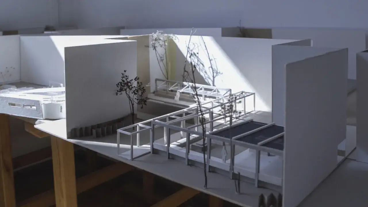 Model architektoniczny z białych kartonów, przedstawiający konstrukcję z elementami zieleni.