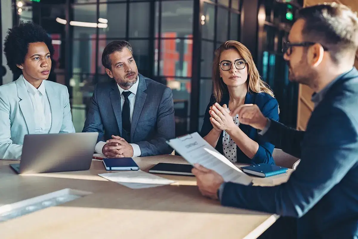 Des hommes et femmes d'affaires discutent autour d'une table, le contrat en main, d&eacute;montrant leur pouvoir de n&eacute;gociation.