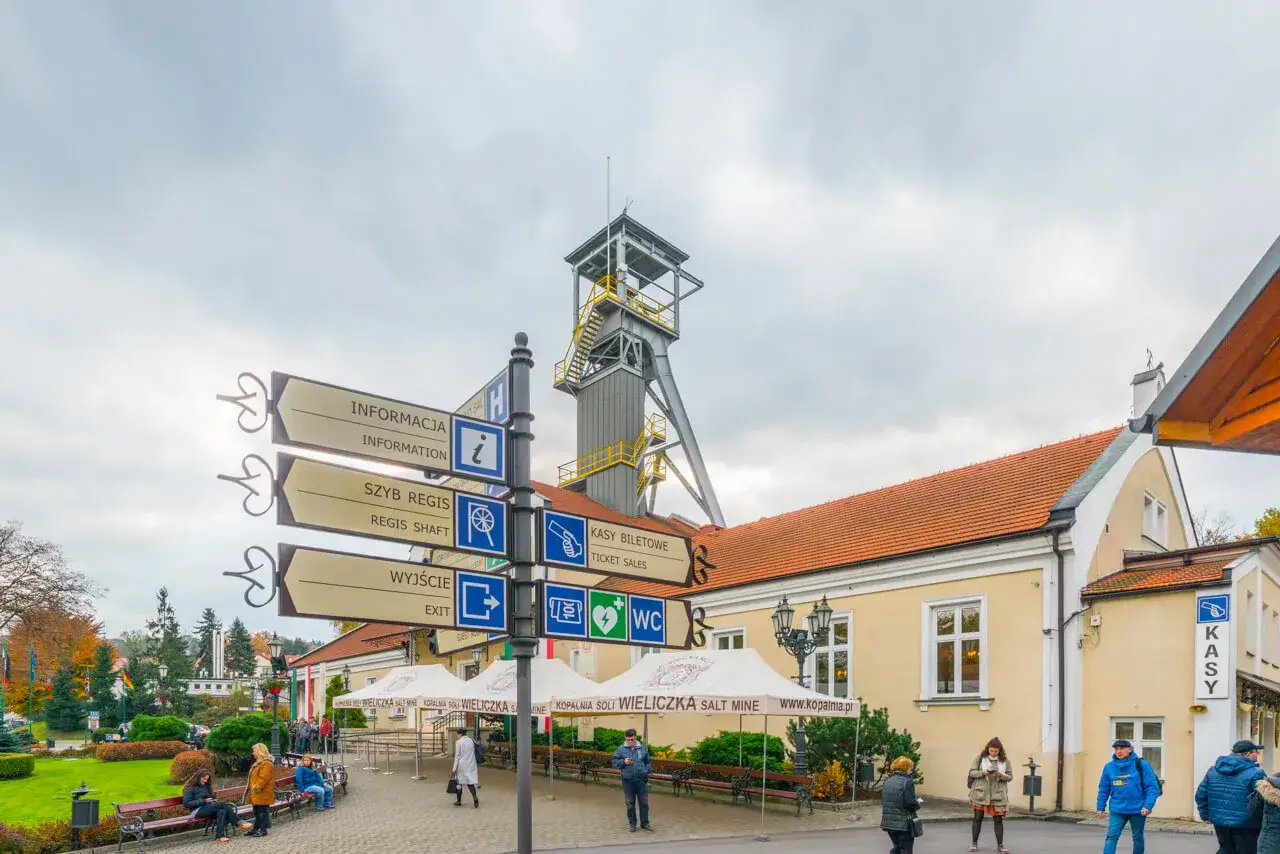 Znaki kierunkowe przy Kopalni Soli Wieliczka, wskazujące drogę do informacji, szybu Regis, wyjścia i kas biletowych.