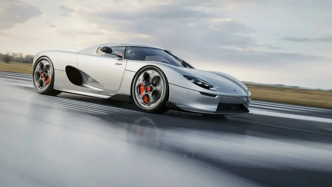En silverfärgad Koenigsegg, en riktigt ny Koenigsegg, susar fram på en bana med molnig himmel.