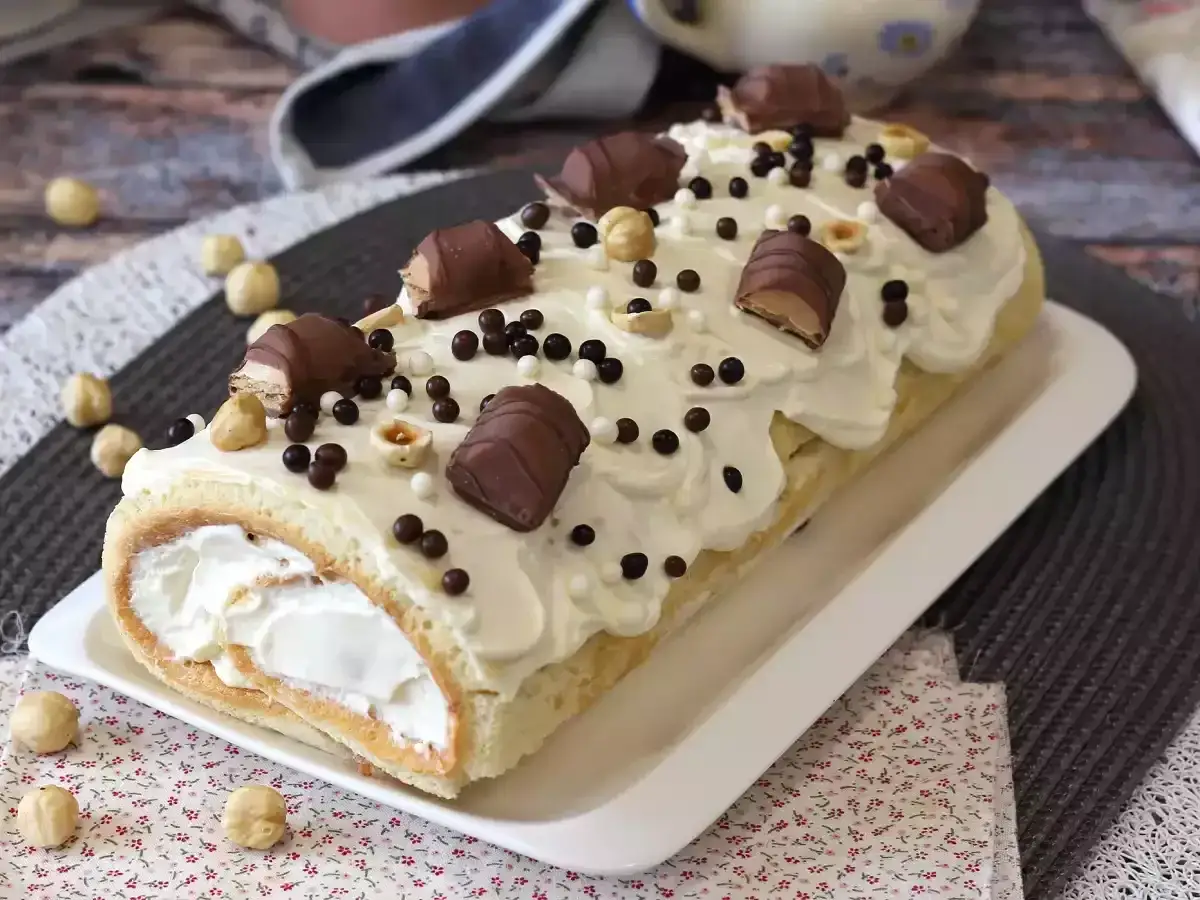 En härlig rulltårta med vit chokladfrosting, chokladbitar och hasselnötter. Perfekt för ett kinder tårta recept!