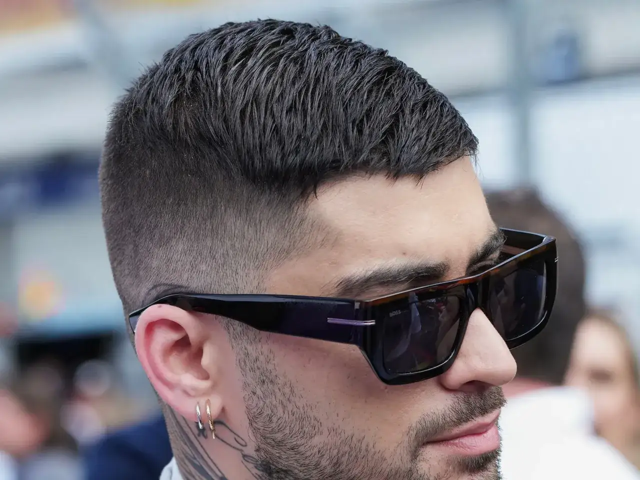 Mann mit spiky hair, Sonnenbrille und Ohrringen.