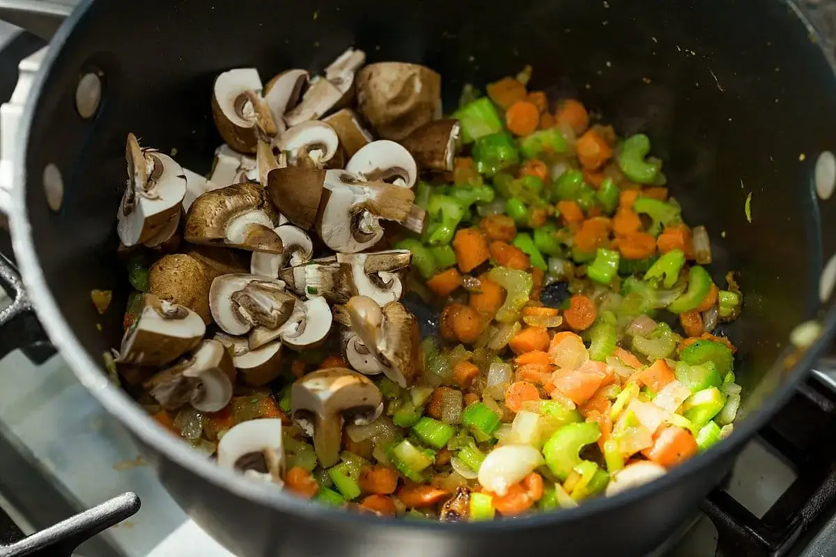 Gehackte Champignons, Karotten und Sellerie in einem Topf, bereit für leckere Champignons Rezepte.