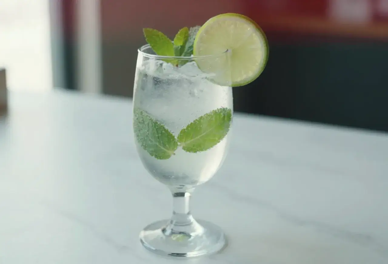 Orzeźwiający, schłodzony mojito bezalkoholowe z listkami mięty i plasterkiem limonki, idealny na upalne dni.