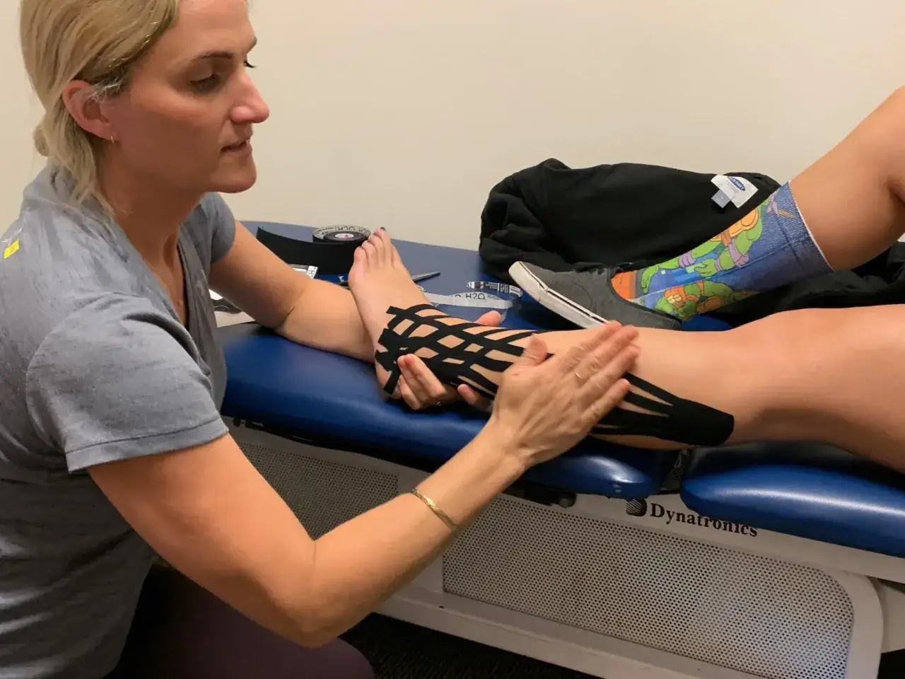 Fisioterapista applica taping alla caviglia per aiutare a camminare con legamenti caviglia rotti.