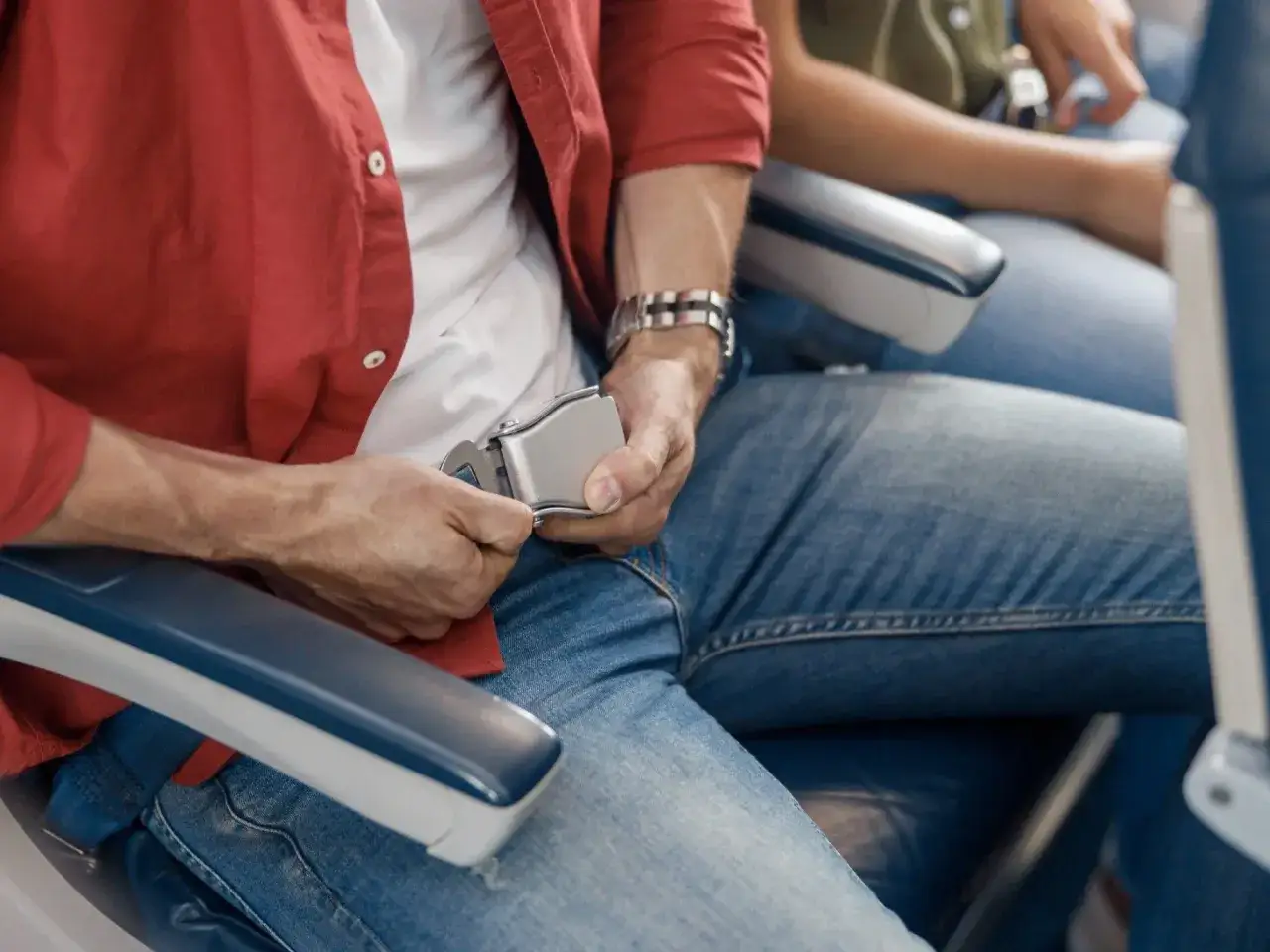 Mężczyzna zapina pas bezpieczeństwa w samolocie. Standardowy pas w samolocie Ryanair ma ok. 100 cm.
