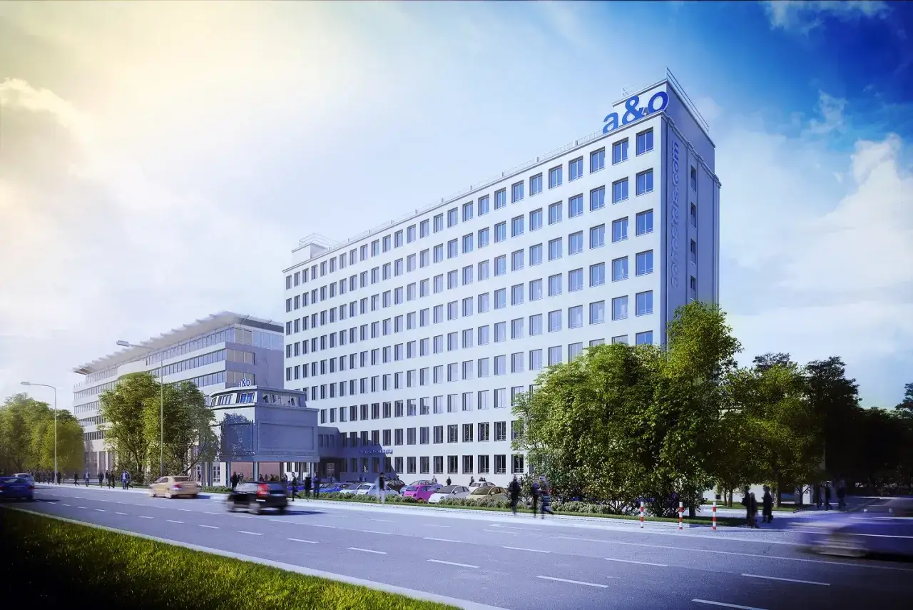 Nowoczesny hotel a&o Warszawa zlokalizowany przy ruchliwej ulicy, otoczony zielenią.