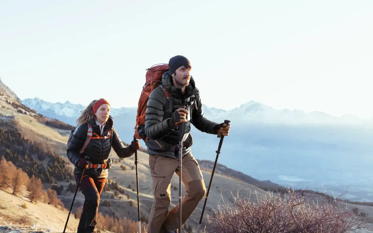 Couple en tenue de randonnée, sac à dos, bâtons. Idéal pour savoir comment s'habiller pour une randonnée en montagne par temps frais.