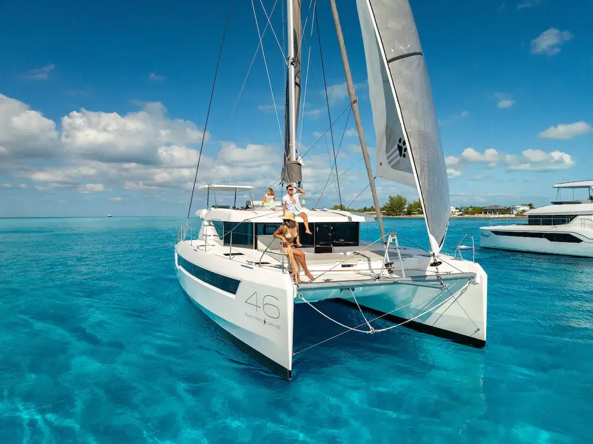 Persone su eleganti **leopard catamarans** navigano in acque cristalline sotto un cielo azzurro.