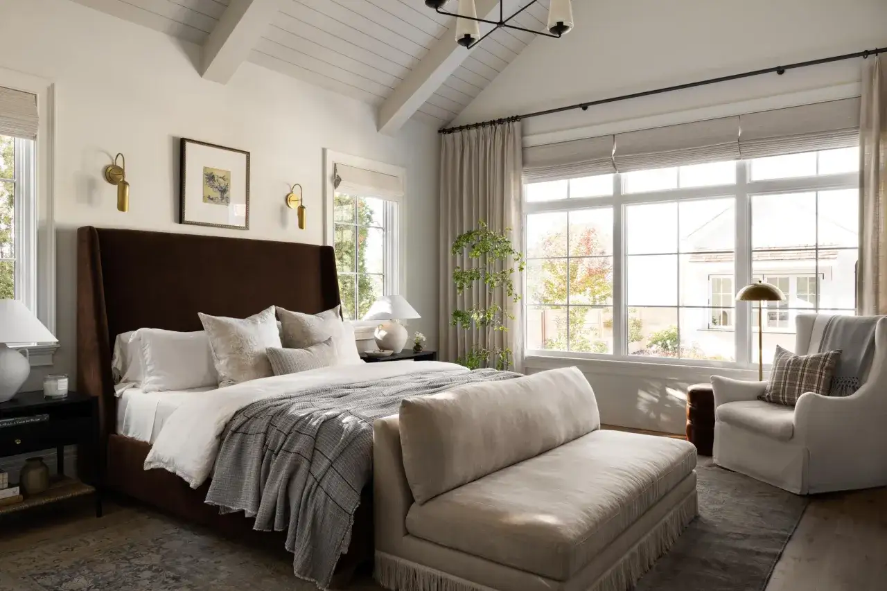 A luxurious bedroom with a tall, dark brown velvet headboard, crisp white linens, and a cozy grey throw. Studio McGee bed styling creates a serene retreat.