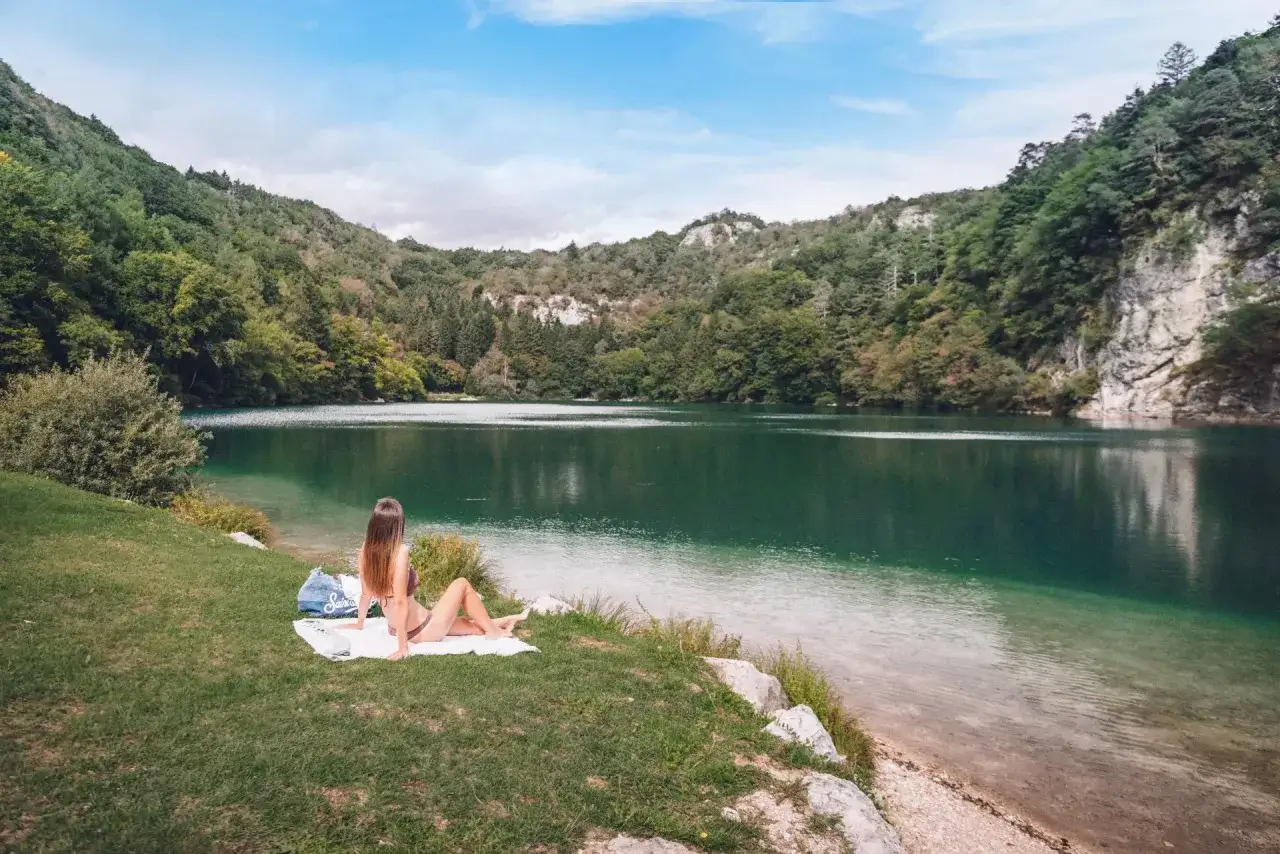 Donna rilassata sull'erba, con vista sul **lago Lamar** e le montagne verdi.