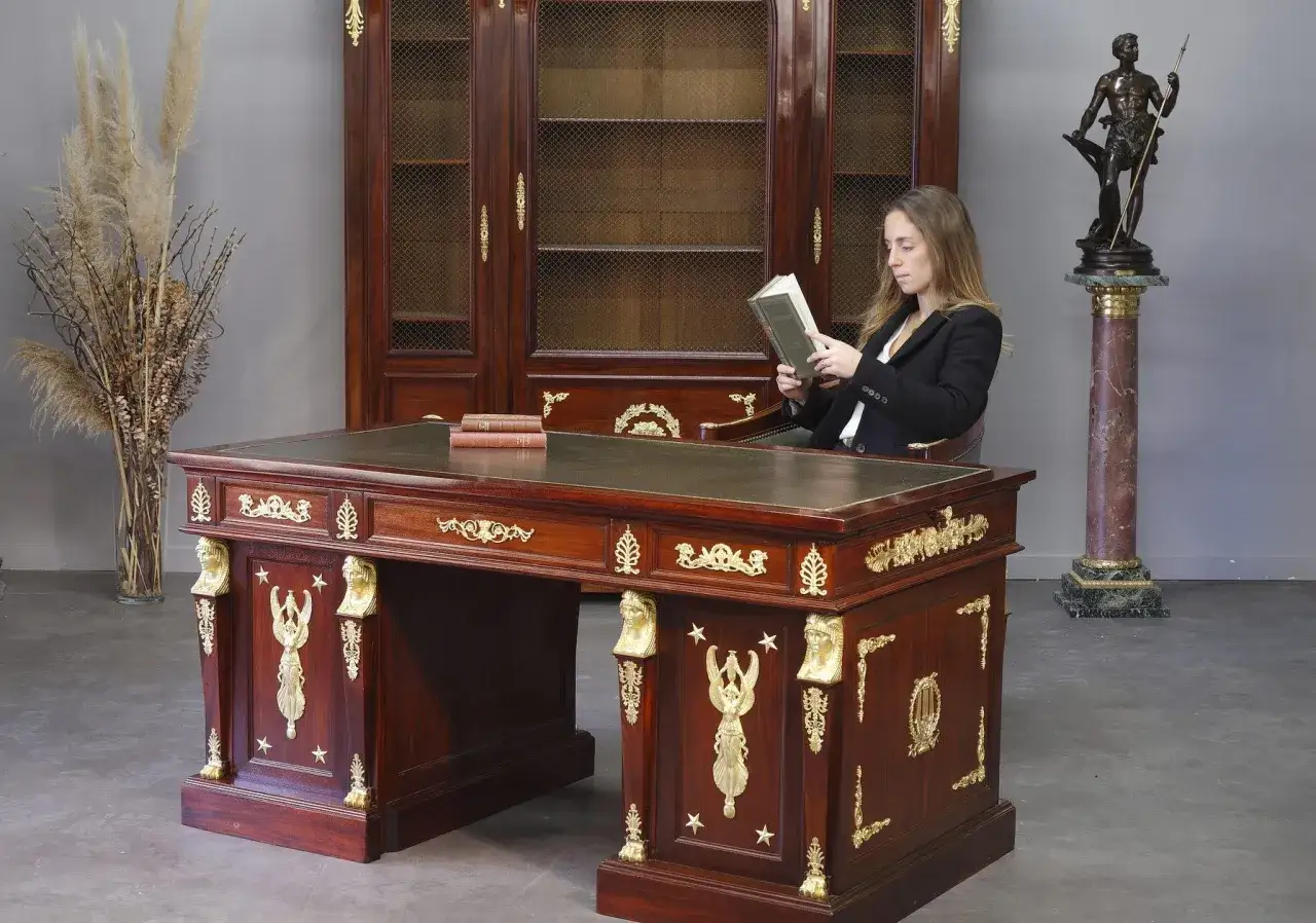 Bureau de style Empire, orné de dorures, avec une femme lisant. Un décor digne d'une époque impériale.
