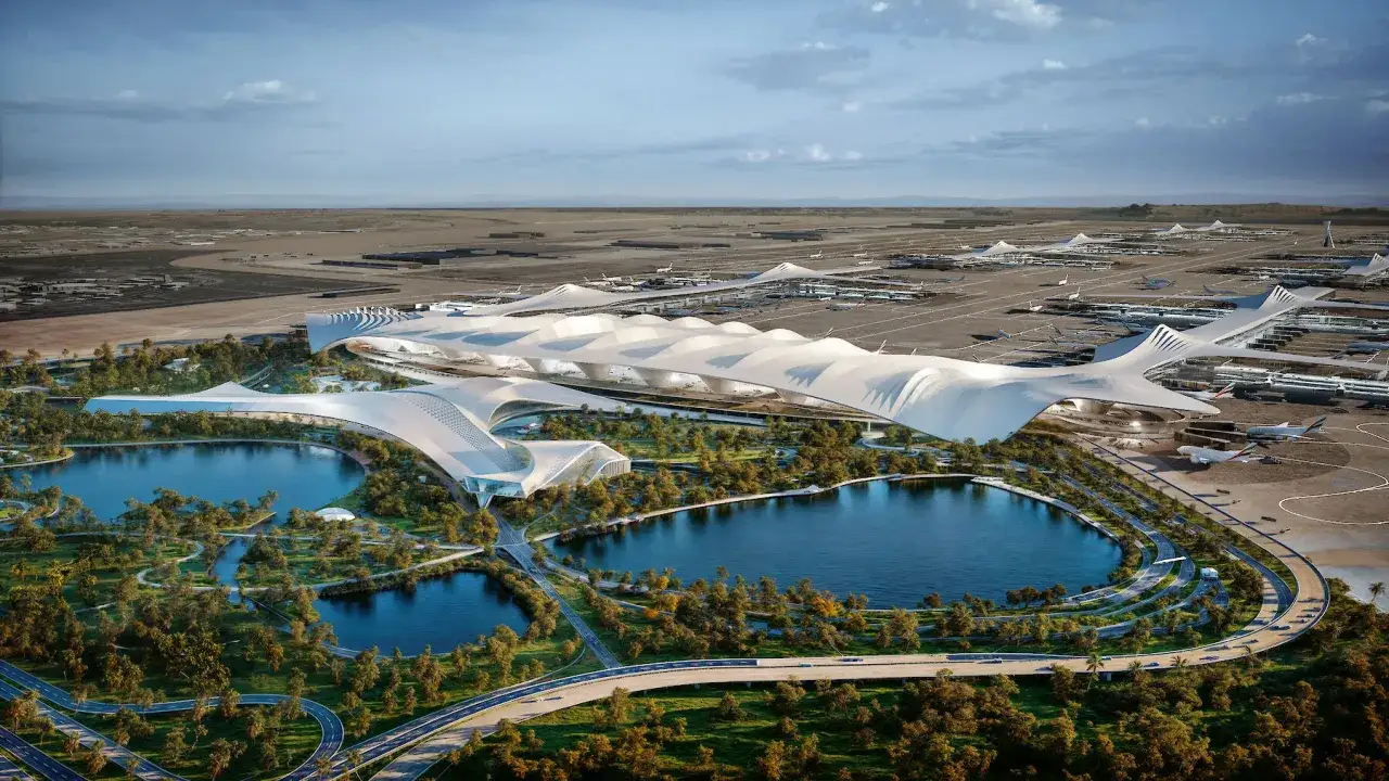 Futurystyczny, biały terminal lotniczy z falującym dachem, otoczony zielenią i jeziorami, z samolotami na płycie. To wizja największego lotniska na świecie.