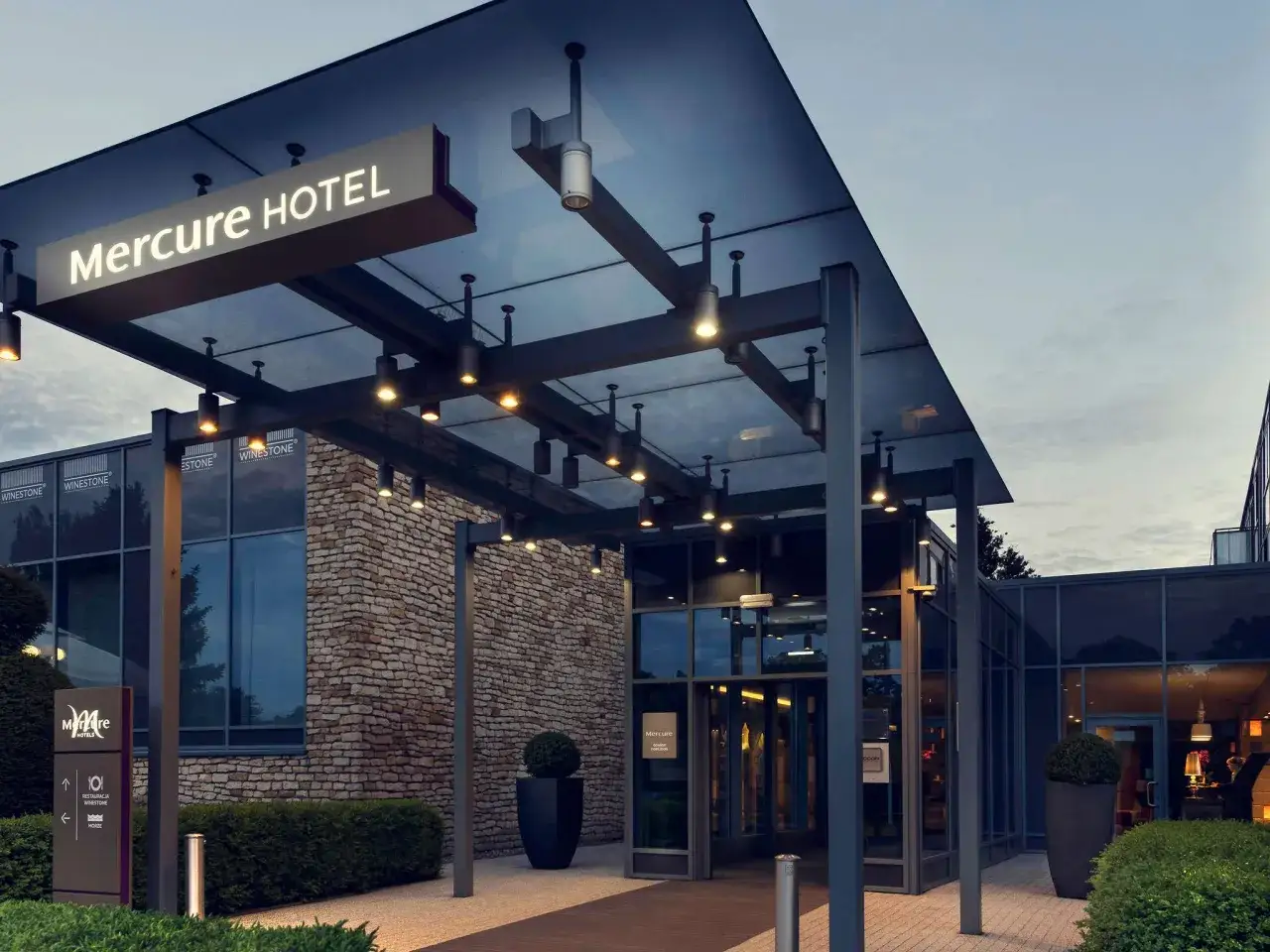 Wejście do hotelu Mercure w Gdańsku. Nowoczesna architektura, kamienna fasada i oświetlony neon