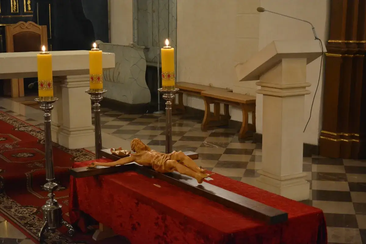 Ołtarz przykryty czerwonym aksamitem, na nim krzyż z postacią Chrystusa. Płonące świece symbolizują liturgia męki pańskiej.