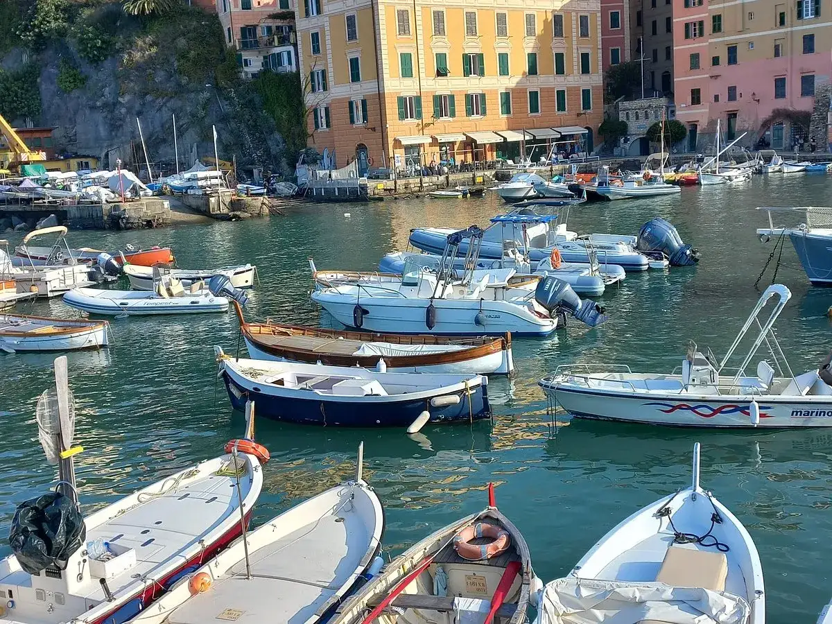 Båtar i hamnen i Camogli, Italien, med färgglada hus i bakgrunden.
