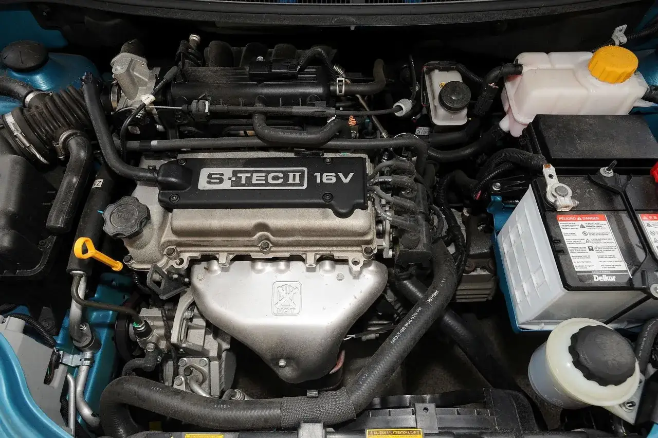 Silnik S-TEC II 16V w Chevrolet Aveo 1.2. Widoczny jest układ dolotowy, akumulator i płyny eksploatacyjne.