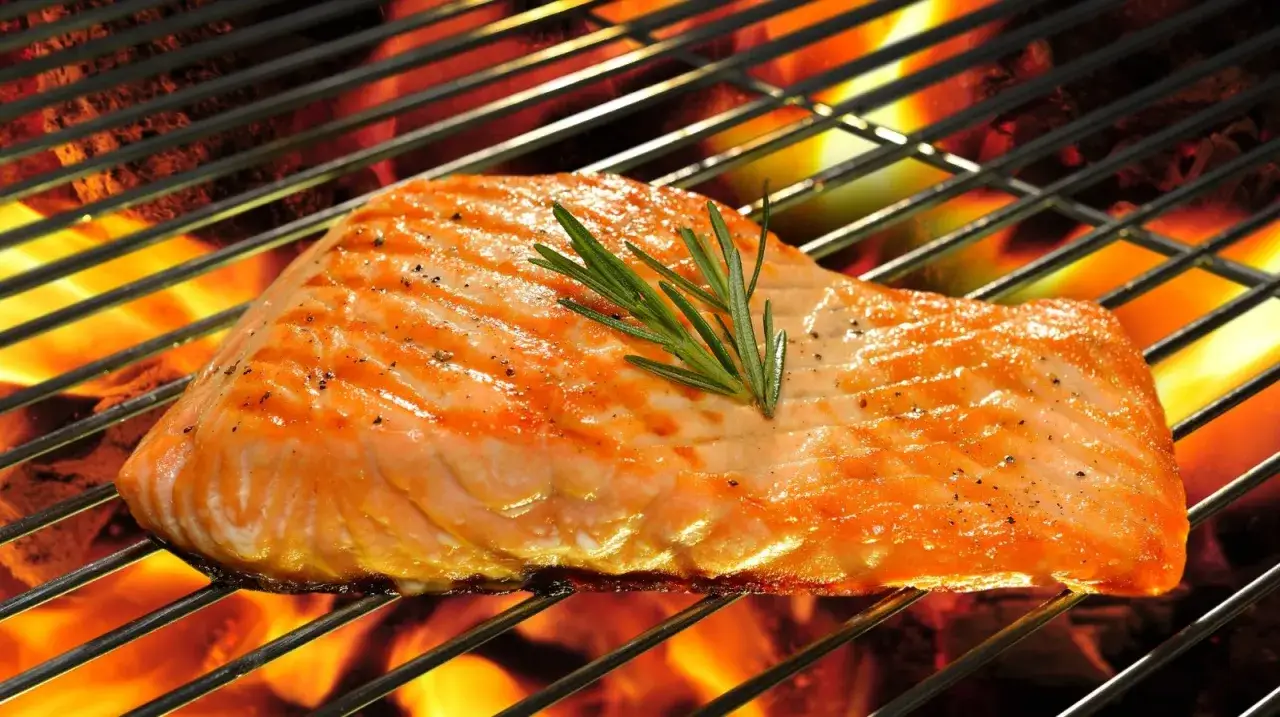 Saftiges Lachsfilet mit Rosmarin auf einem Elektrogrill, das Aroma des Fischgrillens liegt in der Luft.