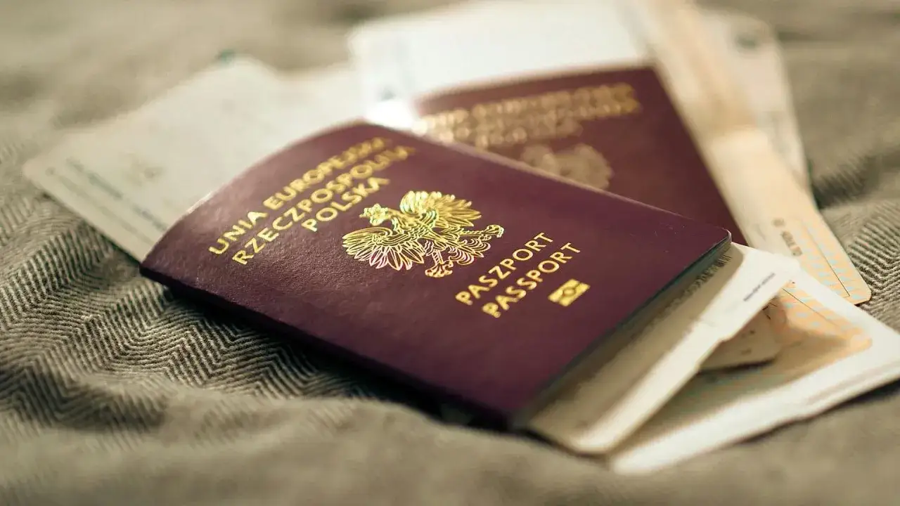 Polskie paszporty leżą na szarej tkaninie. Czy można odebrać paszport z upoważnieniem? To pytanie, na które odpowiedź znajdziesz w urzędzie.