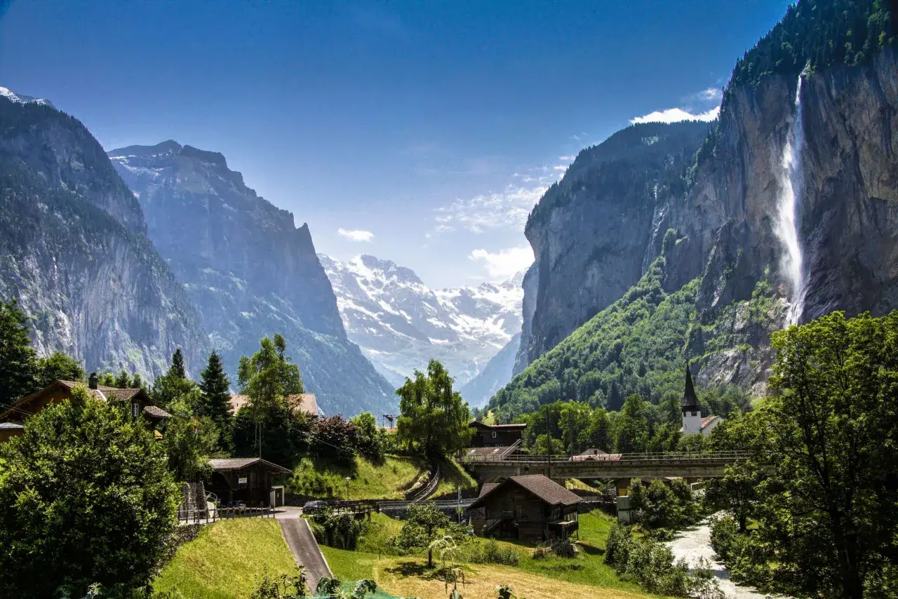 Das Tal von Lauterbrunnen mit seinem majestätischen Wasserfall, umgeben von grünen Hängen und schneebedeckten Gipfeln.