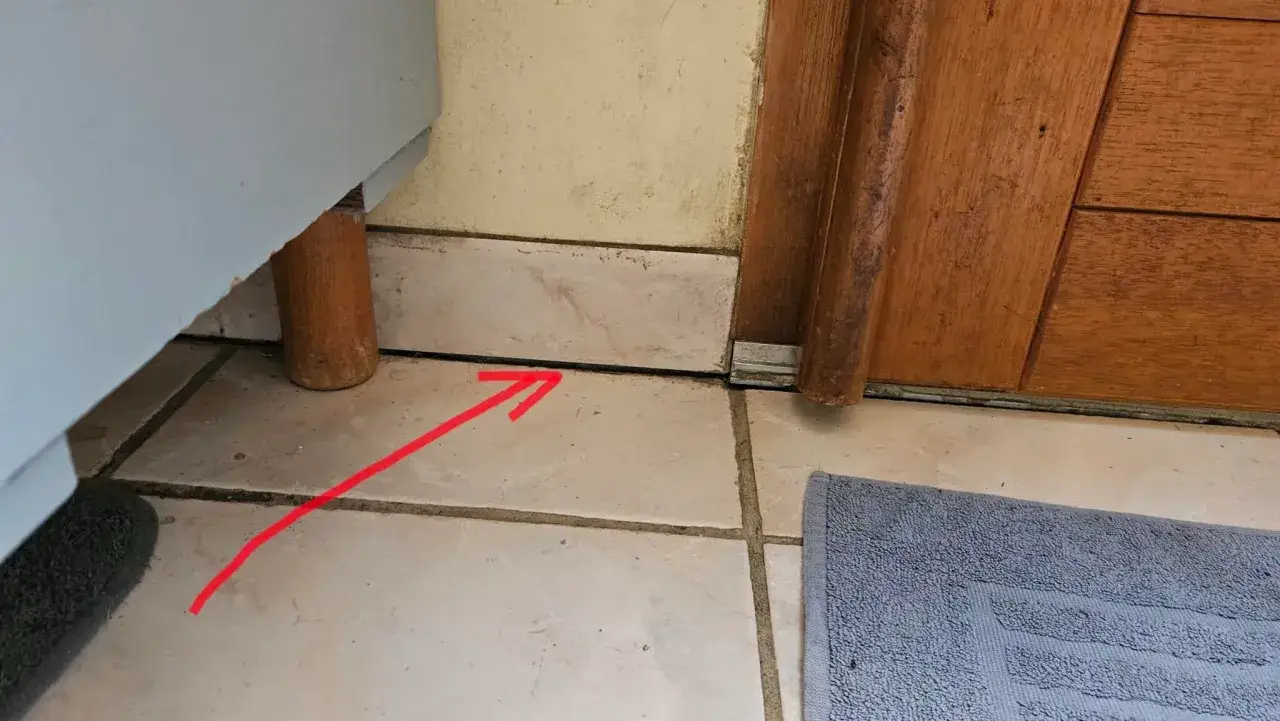 Un affaissement de terrain a créé un espace sous le meuble, visible par la flèche rouge.
