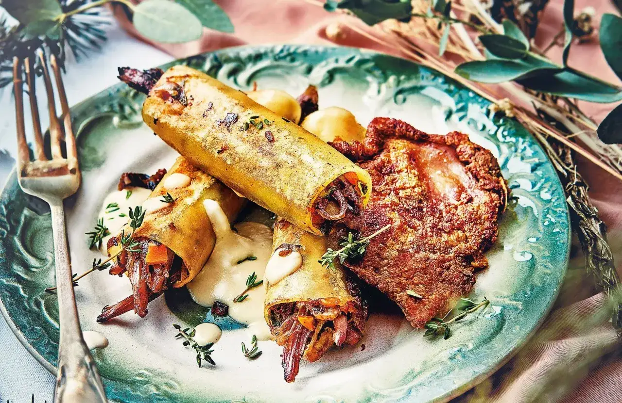 Délicieuse recette gourmande salée : cannellonis farcis à la viande et légumes, nappés d'une sauce crémeuse, accompagnés d'une pièce de viande croustillante.