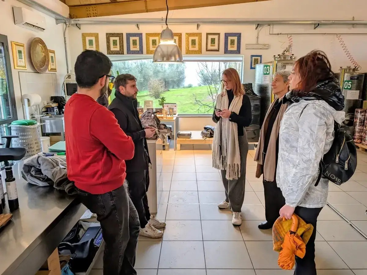 Gruppo di persone in visita in un'azienda agricola, forse per degustare prodotti tipici del **canino Viterbo**.