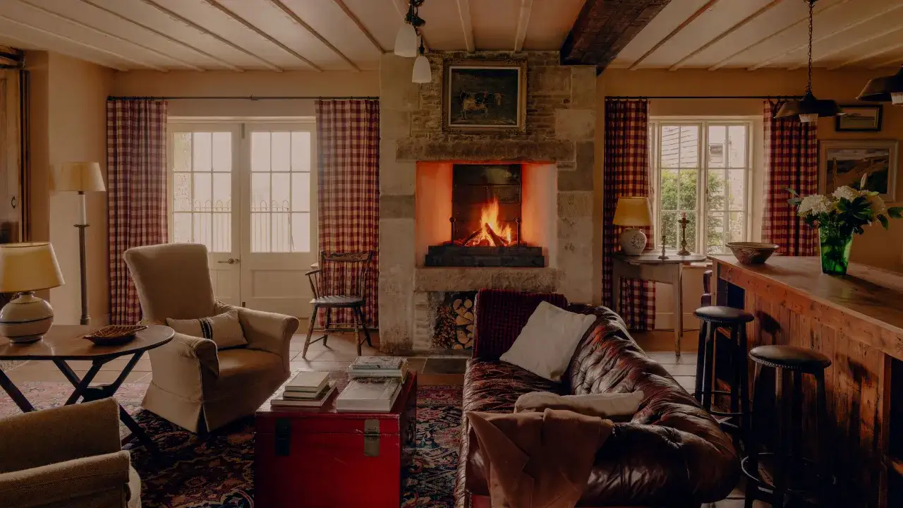 Cozy living room with a crackling fireplace, leather sofa, and armchairs. The simplicity interior design creates a warm and inviting atmosphere.