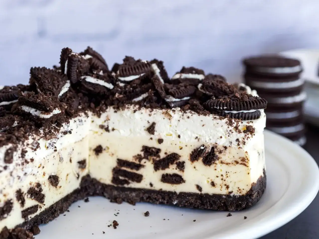 Pyszny sernik oreo na zimno, z kawałkami ciastek w kremowej masie i na spodzie z ciastek.