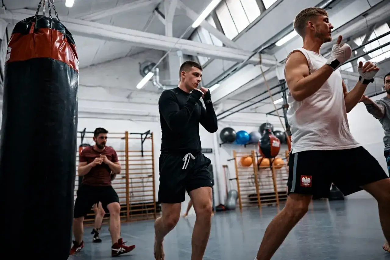 Mężczyźni trenują boks w sali treningowej. Szukasz miejsca, gdzie trenować crossfit w Łodzi? To może być dobry wybór.