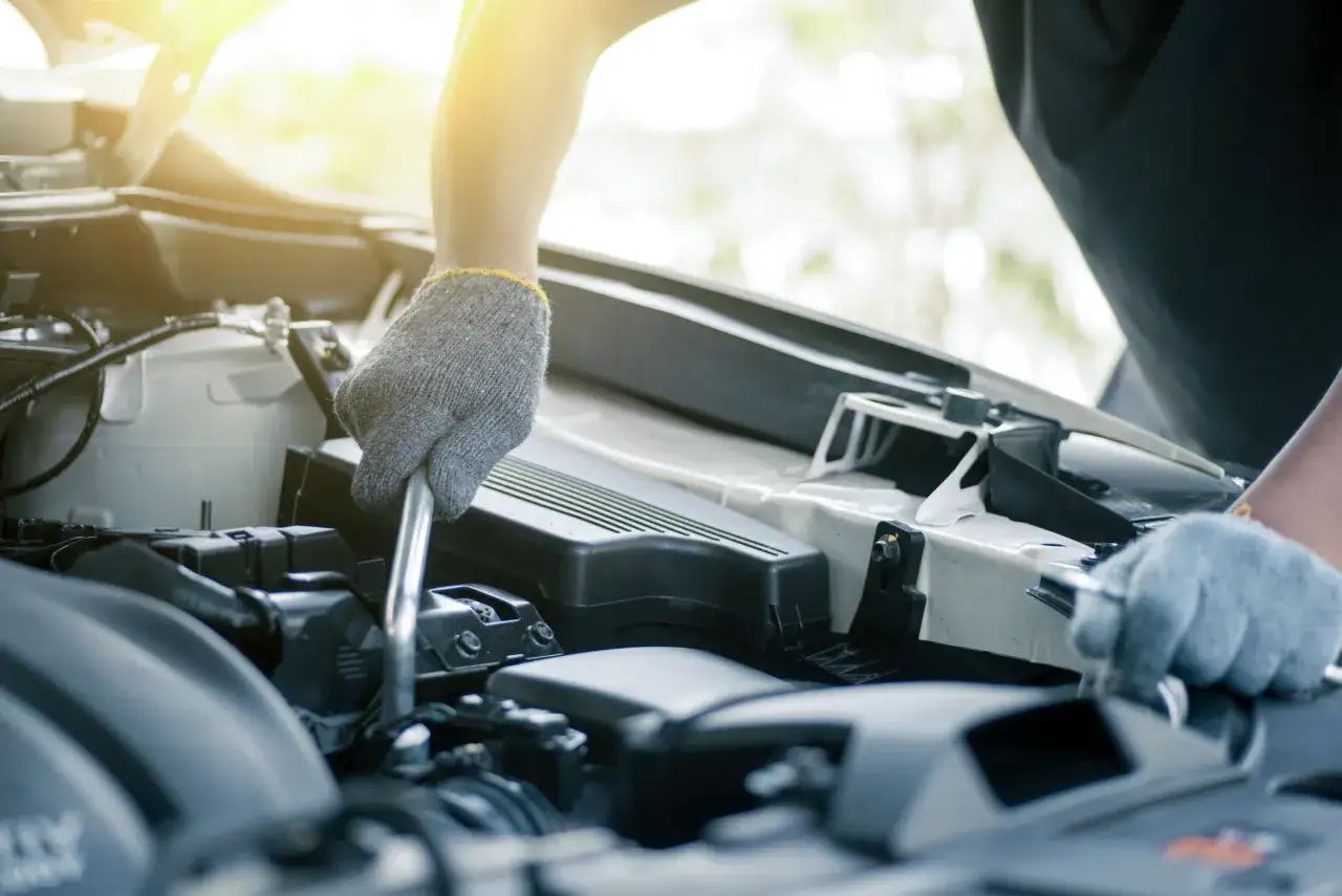 Mechanik w rękawiczkach przy silniku, być może próbuje dowiedzieć się, jak wyłączyć alarm w samochodzie.