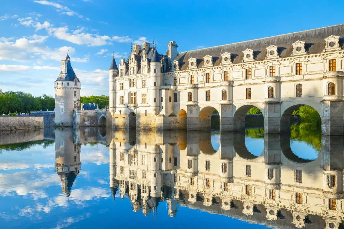 Castillo de Chenonceau, uno de los monumentos de Francia m&aacute;s bellos, reflejado en el r&iacute;o Cher bajo un cielo azul.