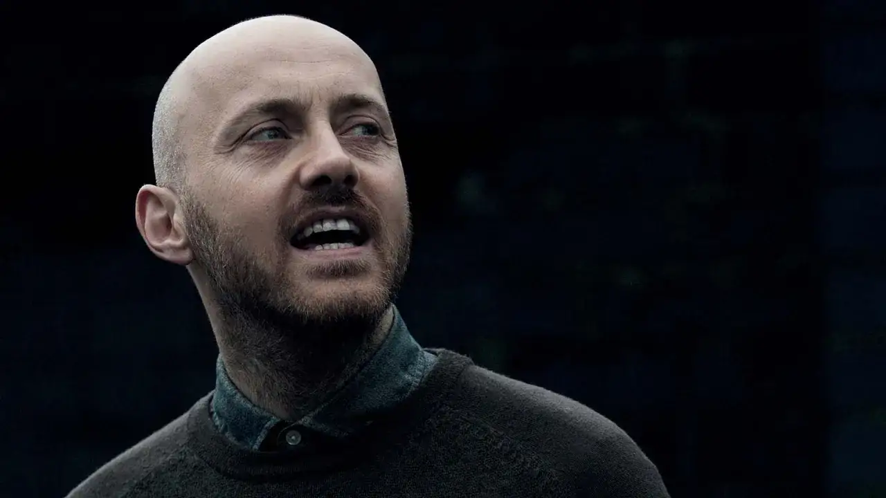A close-up of Justin Parker, a bald man with a beard, looking off to the side with his mouth open.