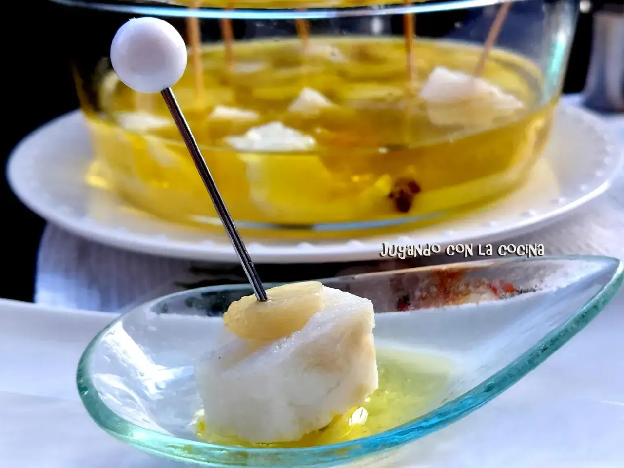 Delicioso bacalao confitado en aceite de oliva, servido en una cuchara de cristal.